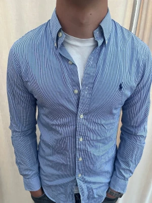 Blårandig skjorta från Ralph Lauren - Riktigt snygg randig skjorta från Ralph Lauren. Strl S, personen på bilden är 185 cm lång. Skicka gärna prisförslag. Kika in min profil för mer schyssta plagg 