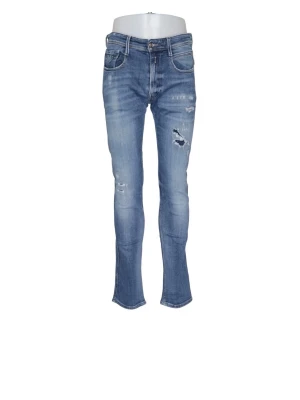 Blå ripped Replay anbass jeans - Säljer ett par ljusblå Replay anbass jeans med slitningar på ena benet. Jeansen har klassisk femficksmodell, låg midja och dragkedja med knapp. Materialet är denim med lite stretch för skön passform. Perfekta för en avslappnad och trendig look.