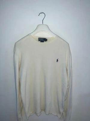 Ralph lauren tröja - Polo Ralph Lauren stickad tröja i ljus färg, perfekt som ett stilrent basplagg.  Tröjan är i storlek S och har slim fit, men tack vare det stretchiga materialet kan den även passa både något mindre och något större storlekar.  Den är ytterst lite använd och har inga större tecken på användning.  Skriv gärna om ni har några frågor!
