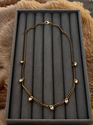 Guldhalsband med hjärtberlocker - Snyggt halsband i guldfärgad metall med små hjärtformade berlocker längs kedjan. Kedjan har en klassisk design och hjärtana ger en söt och trendig touch. Perfekt accessoar för att lyfta vilken outfit som helst.