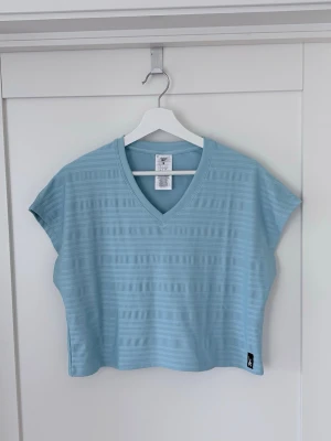 Ljusblå meshtröja från Reebok - Reebok perforated t-shirt - Blue Pearl har inbyggt mesh som håller dig ventilerad.  Regular fit har ett rakt snitt med utrymme att röra sig naturligt.    [REE] CYCLED: Konstruerad med 85 % återvunnen polyester och 15 % elastan. Längd 49 cm. Axelbredd ca 49 cm. Svårmätt bred pga passformen.   Inköpt för 539kr. Aldrig använd!  