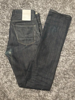Denham selvedge  - Snygga mörkblå jeans från Denham i storlek W31 & L34, med slim fit passform. Klassisk femficksmodell med kontrastsömmar och läderpatch bak i midjan. Tillverkade i slitstarkt och tåligt denimtyg med selvedge. Som ger ett utseende utan dess like och stilren look.