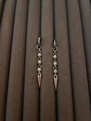 Silvriga örhängen med pärlor och spikes - Säljer ett par coola silvriga örhängen med små vita pärlor och spetsiga spikes längst ner. Örhängena har en tunn ring som fäste och hängande kedja med pärlor. Perfekt för dig som gillar edgy och stilrena accessoarer.