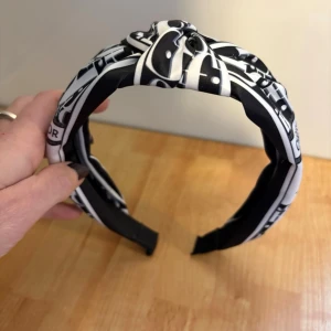 Diadem - Svart/vitt diadem med text på. En knut mitt uppepå. Aldrig använt!