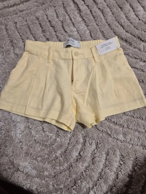 Ljusgula linneshorts från Hollister i storlek xxs - Säljer ett par supergulliga ljusgula shorts från Hollister i linne med prislapp. De har låg midja, bälteshällor, knapp och dragkedja framtill samt fickor på sidorna. De har oxå en stretchig midja. Perfekta nu för varma sommardagar och ger en fräsch look. Skriv gärna om frågor eller prisförslag ❤️❤️❤️