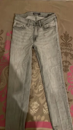 Ljusgrå jeans - Säljer ett par ljusgrå skinny jeans med klassisk femficksmodell och raka ben. Jeansen har en tvättad look och är perfekta för en avslappnad stil. Materialet är troligtvis bomull med stretch för extra komfort.