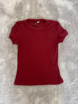 Vinröd t-shirt från H&M  - En enkel och stilren vinröd t-shirt från H&M. Modellen har rund halsringning och korta ärmar. Tillverkad i mjuk bomull som känns skön mot huden. Perfekt basplagg att matcha med allt i garderoben.
