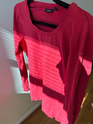 Röd långärmad topp från Lindex - En enkel och stilren röd långärmad topp. Toppen har rund halsringning och är gjord i mjuk bomull, perfekt för en avslappnad look. Passformen är normal och materialet känns skönt mot huden🥂