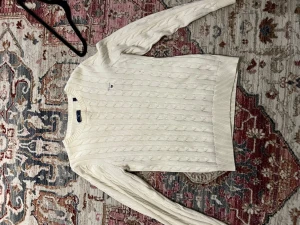 Vit kabelstickad tröja från Gant - Kabelstickad vit tröja från Gant med rund halsringning och diskret logga på bröstet. Tröjan har långa ärmar och ribbade muddar vid ärmslut och nederkant. Perfekt för lager-på-lager och klassisk stil.