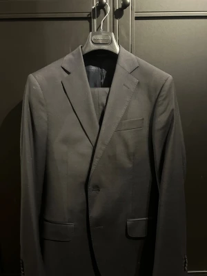 Oscar Jacobson Kostym - Tjena! Säljer nu min mörk blå Oscar Jacobson kostym då jag har vuxit ur den. Självfallet får du både kavaj och byxorna. Har använt den ungefär 3-4 gånger så den är som ny! Byxorna är storlek 46 och kavajen storlek 48. Org pris: 5999kr 