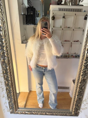 Vit fluffig pälsjacka från Lanshifei - Säljer en supermjuk och fluffig vit pälsjacka från Lanshifei. Jackan har lång luggig fuskpäls, helvit insida och stängs med hakar framtill. Perfekt för dig som vill sticka ut och hålla dig varm med stil.