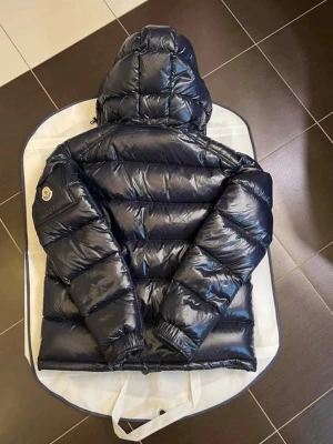 Mörkblå glansig dunjacka från Moncler - Säljer nu min Maya moncler jacka i mörkblå (ser svart ut). Inga defekter förutom att vänster dragkedja lossnat (se på bild 3). Den går dock att sätta tillbaka om man går till en skräddare och man får självklart med dragkedjan. Skriv för fler bilder❤️ 