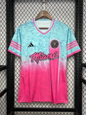 Inter Miami FC rosa/blå matchtröja - Snygg matchtröja från Inter Miami FC i en färgstark mix av ljusblått och rosa med palmmönster. Tröjan har V-ringning, korta ärmar och Adidas logga på bröstet. Miami-text och klubbmärke framtill. Perfekt för fotboll och streetwear.