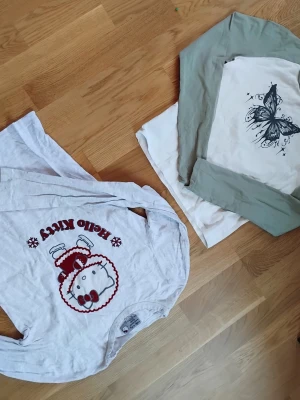 2 långärmade tröjor:Hello Kitty & fjäril - Två simpla tröjor: en med justera och en med en fjäril. Båda är i ungefär samma storlek. Går att stayla på många olika sätt. Passar främst för 9-12 åringar. 