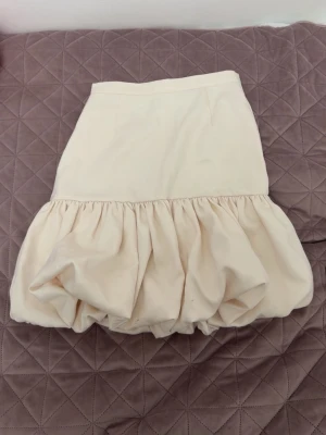 Beige kjol med ballongform - Aldrig använt!! En beige kjol med volang och ballongformad nederdel. Den kan även se lite krämvit ut. 