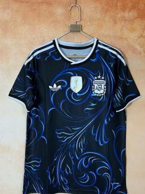 Argentina VM tröja - Snygg svart fotbollströja från Adidas med Argentinas landslagslogga och FIFA-märke på bröstet. Tröjan har ett unikt blått och lila mönster över hela tyget, vita detaljer på axlar och krage samt korta ärmar. Perfekt för dig som älskar fotboll och vill sticka ut på planen. Du kan bestämma vilken storlek du vill ha!!! Det kan ta upp till 15-20 dagar till att tröjan är framme!!! 