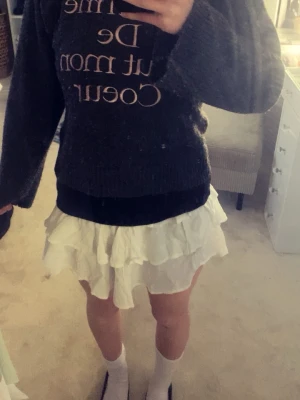 Ginatricot - Mysig svart stickad tröja med vitt texttryck 'Je t'aime De Tout mon Coeur' på framsidan. Tröjan har rund halsringning och långa ärmar. Perfekt för dig som gillar en avslappnad och trendig stil.