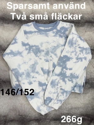 Blåvit tie-dye sweatshirt - Cool sweatshirt i blåvitt tie-dye-mönster med rund hals och långa ärmar. Tröjan har ribbade muddar vid ärmslut och nederkant. Perfekt för en avslappnad och trendig look. 🌸 Kortare modell. Sparsamt använd. Två små fläckar. Storlek 146/152