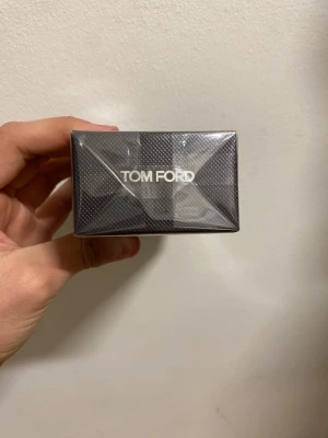 Tom Ford,oud - Snygg parfym från Tom Ford i en elegant svart, mönstrad kartong med silvrig text. Förpackningen har en lyxig känsla och är tillverkad av kartong med plastfilm runt. Perfekt för dig som gillar exklusiva dofter och stilren design.