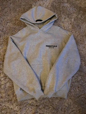 Essentials hoodie  - Säljer en snygg grå hoodie från essentials. Hoodien är knappt använd då den är i fel storlek, i princip som ny skick. Det finns inga defekter på hoodien