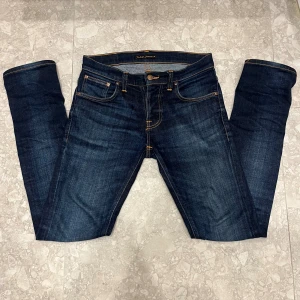 nudie jeans - storlek 28/32 passar 29/32 Säljer ett par mörkblå jeans från Japan Blue med klassisk femficksdesign och kontrastsömmar. Jeansen har raka ben och är tillverkade i kraftig denim som ger en snygg tvättad look. Perfekta för dig som gillar stilrena och tidlösa jeans.
