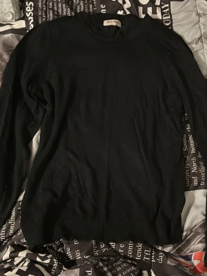 Svart tröja från Beyond Retro - Klassisk svart tröja från Beyond Retro med rund halsringning och långa ärmar. Tröjan har ribbade muddar vid ärmslut och nederkant, vilket ger en snygg och enkel look. Perfekt basplagg i garderoben.