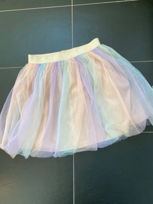 Pastellfärgad tyllkjol från SHEIN mini strl M - Söt kortkjol från SHEIN i flera pastellfärger med ett fluffigt lager av tyll. Kjolen har bred resår i midjan och är perfekt för dig som gillar en lekfull och färgglad stil. Materialet är syntet och kjolen har en lätt och luftig känsla.