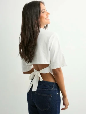 Vit topp med knyt - Säljer en vit topp i bomull med korta ärmar och knytband i ryggen. Enkel och clean design som passar perfekt till jeans eller kjol. Rund halsringning och mjukt material för en avslappnad look. Köparen står för eventuell frakt.