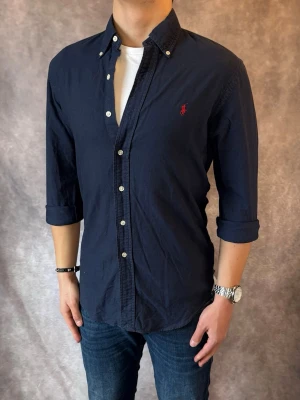 Marinblå Ralph Lauren Skjorta - Stl S, Slim fit - RIKTIGT FET RL SKJORTA I FÄRGEN MARINBLÅ MED RÖD PONY, perfekt till sommaren som närmar sig! 🏖️🌊 | Mycket bra skick: 9,5/10, utan defekter! | Stl: S |  Modellen är 176cm och väger 75kg,  | Hör av dig vid frågor // Galgen 🫡