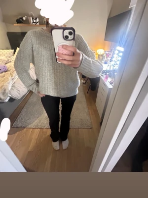 Ljusgrå stickad tröja i relaxed fit - Mysig ljusgrå stickad tröja med rund hals och avslappnad passform. Tröjan har långa ärmar och är ribbstickad i ett mjukt material, perfekt för kyliga dagar. Enkel och stilren design som passar till det mesta.