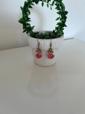 3 Guldiga örhängen med frukter i - Säljer 3 par unika örhängen med guldfärgade krokar och detaljer samt klara glaskulor fyllda med små frukter.Perfekta för dig som vill ha något färgglatt och annorlunda i öronen. Passar till många olika stilar och outfits.