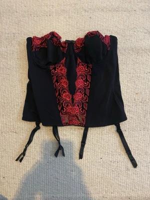 Snygg svart och röd korsett-top - Jättefin topp/undertröja i svart färg med röd spets, storlek 36C, skriv om ni vill ha nått mått så fixar jag! <3  Priset kan diskuteras, tar gärna emot bud! :))