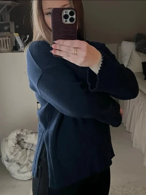 Mörkblå stickad tröja - Mysig mörkblå stickad tröja med ribbad hals och slitsar i sidorna. 