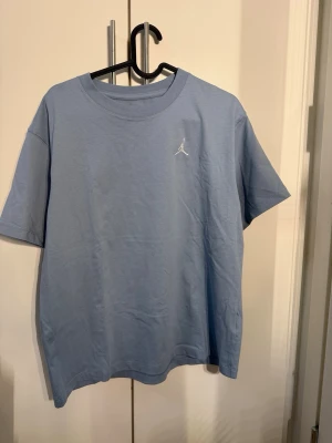 Ljusblå Jordan t-shirt i bomull - Snygg ljusblå t-shirt från Jordan med klassisk rund hals och korta ärmar. Tillverkad i mjuk bomull och har en liten vit Jordan-logga broderad på bröstet. Perfekt för en avslappnad och sportig stil.