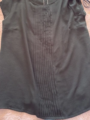 Mörkgrön ärmlös topp från Anna Field - Stilren mörkgrön topp från Anna Field med ärmlös design och dekorativa vertikala sömmar framtill. Perfekt till jeans eller kjol för en clean look. Tillverkad i ett mjukt, lätt material som känns skönt mot huden.