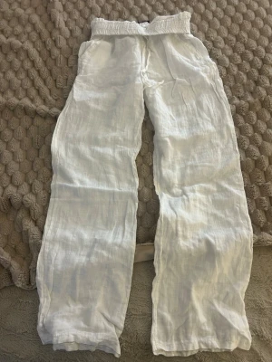 Vita linnebyxor från Chelsea - Säljer ett par vita linnebyxor från Chelsea i storlek XS. Byxorna har resår i midjan och raka ben, vilket ger en avslappnad och skön passform. Tillverkade i tunt och luftigt linne, perfekta för varma dagar. Endast använda ett fåtal gånger.