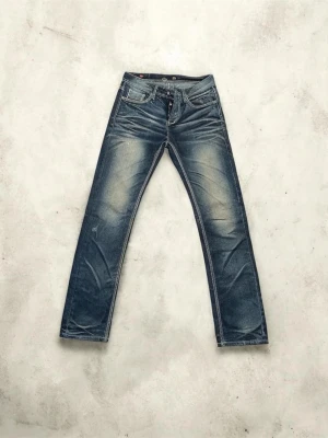 Blå slim straight jeans med slitningar - Säljer ett par blå slim fit jeans med snygga slitningar och tvättade detaljer. Jeansen har klassisk femficksmodell, normal midja och dragkedja. Perfekta för en avslappnad och trendig look.