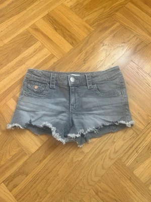 Grå jeansshorts med fransig kant från Gina tricot💕💕💕💕💕 - Säljer ett par grå jeansshorts med fransig, rå kant och klassisk femficksdesign från Gina Tricot 💕💕💕💕💕. Shortsen har bälteshällor, knapp- och dragkedjestängning samt bakfickor med lock och knapp.💕💕💕💕I mycket bra skick💕💕💕💕Jag säljer dem för 75 kr💕💕💕Hör av er vid intresse💕💕💕💕💕