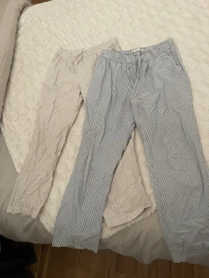 Randiga ”linnebyxor” i blått och beige - Två par ”linnebyxor” med ränder, ett par i ljusblått och ett par i beige. 50 kr/st, båda för 80 kr. 