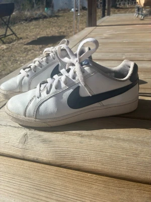 Vita Nike sneakers med blå swoosh - Nike sneakers säljes Använda skor med synliga fläckar och slitage, men fortfarande hela och fullt användbara. Inga hål eller trasiga delar. Perfekta som extra-/vardagsskor. 