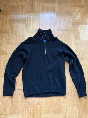 Svart stickad tröja med halv dragkedja från Jack & Jones - Svart stickad tröja med hög krage och halv dragkedja. Tröjan har ribbstickade muddar. Perfekt för kalla dagar och enkel att matcha med andra plagg. Använd sparsamt, skriv vid funderingar ☺️