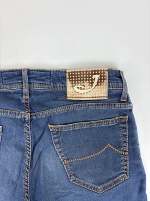 Blå jeans från Jacob Cohen - Snygga blå jeans från Jacob Cohen med klassisk femficksmodell och raka ben. Jeansen har kontrastsömmar och ett unikt beige patch med J-logga bak i midjan. Tillverkade i mjuk denim som ger en skön passform och stilren look.