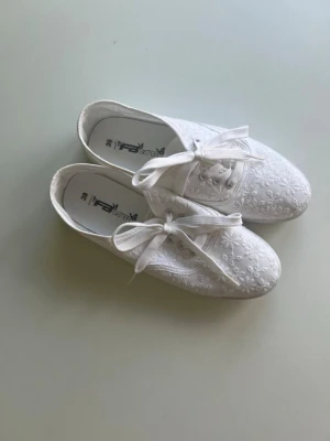 Vita sneakers - Snygga vita sneakers från NewYorker med spetsdetaljer och klassisk låg modell. Passar perfekt till studenten eller bara fina sommarskor. Använda endast en gång!