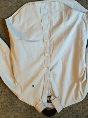 Ljusblå skjorta från polo Ralph lauren - Klassisk ljusblå skjorta från polo med button-down krage och broderad logga på bröstet. Skjortan har långa ärmar och knäppning framtill. Perfekt till jeans eller chinos för en clean och stilren look.