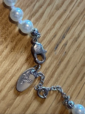 Pärlhalsband från Vivienne Westwood - Snyggt halsband från Vivienne Westwood med vita pärlor och silverfärgade detaljer. Halsbandet har en ikonisk orb-tag i metall och justerbar kedja. Perfekt accessoar för att lyfta din outfit.