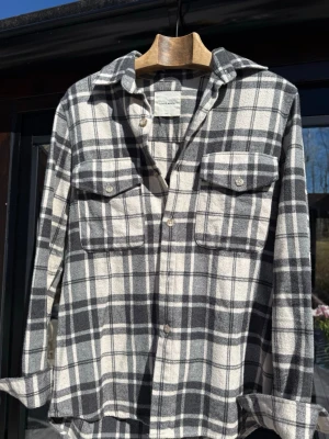 A Day's March skjorta - Snygg rutig flanell skjorta i svart och vitt från A Day's March. Skjortan har två bröstfickor med knappar och klassisk krage. Tillverkad i mjuk bomull, perfekt för lager på lager och chill stil. Väldigt bra skick, storlek s men lite större i storleken. Skriv vid frågor!