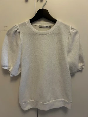 Vit puffärm topp från 157 - Säljer en vit topp från 157 med puffärmar och rund halsringning. Materialet är mjukt och har en lätt struktur. Perfekt för dig som gillar en enkel men trendig stil. Passar till både jeans och kjol.