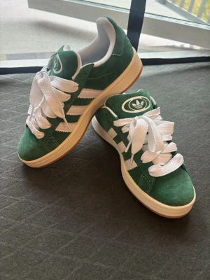 Adidas gröna sneakers / Campus stil, nyskick 💚🤍 - Säljer ett par superfina gröna Adidas sneakers i mocka med vita detaljer och tjukt snörning, väldigt trendiga! ✨  Använda endast 1 gång, i princip nyskick. Inga större märken eller slitage, sulan är nästan som ny.  Perfekta till vardag, skola eller som snygga sneakers till outfit 🌿  📏 Storlek: 38 2/3 📍 Skick: 9.5/10, använda en gång 🚚 Kan skickas eller mötas upp  Skriv vid frågor eller fler bilder 💌