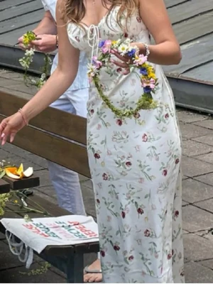 Satin Vit blommig klänning med snörning - Söt vit klänning med små blommor och smala axelband. Klänningen har snörning framtill vid bysten och en figurnära passform. Perfekt för varma dagar och har en romantisk känsla. Lånade bilder. Helt ny med lappar