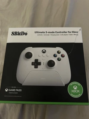 8BitDo Ultimate 3-mode Xbox-kontroll - Snygg vit 8BitDo Ultimate 3-mode handkontroll för Xbox. Ergonomisk design med klassiska svarta knappar och styrspakar, samt färgade ABXY-knappar. Kompatibel med Xbox och inkluderar Xbox Game Pass-kort. Perfekt för gaming på konsol.
